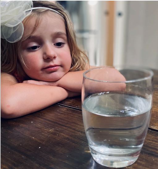Young girl looks at glass of water