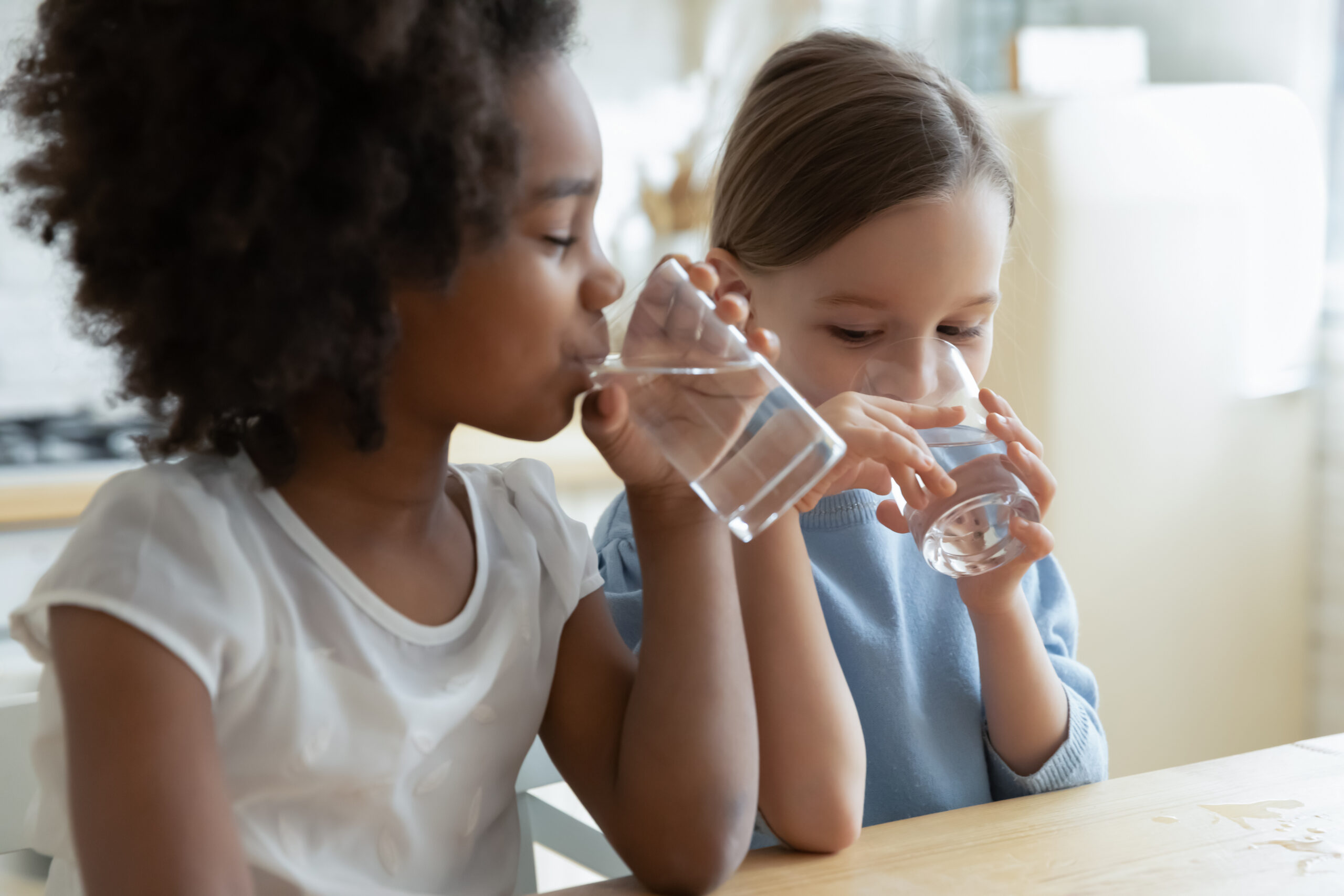 Two girls drink glasses of water